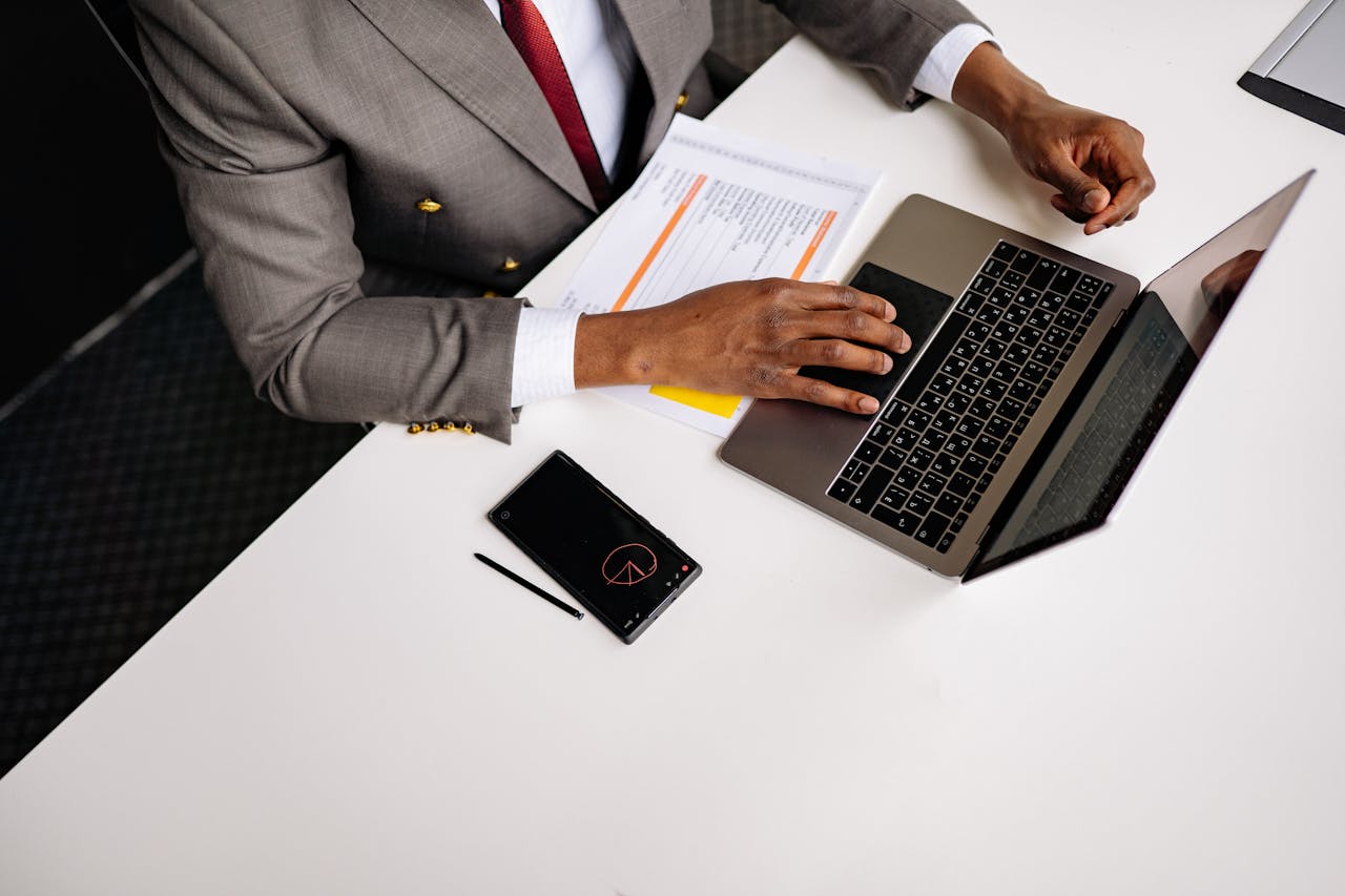 A business professional wearing a gray suit working on a laptop in an office setting.